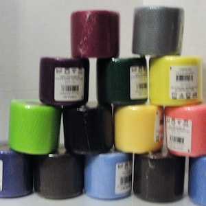 May include: A stack of 14 rolls of tulle fabric in various colors, including green, blue, yellow, pink, purple, and gray. Each roll has a label with care instructions and a barcode.