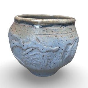 May include: A handmade ceramic bowl with a speckled, light blue glaze. The bowl features a textured surface with embossed floral designs around the exterior. The rim is a darker shade of blue and brown.