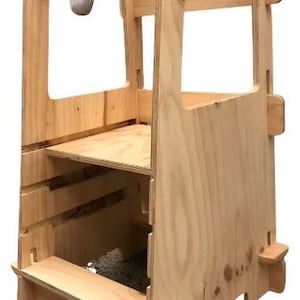 Puede incluir: Una torre de aprendizaje de madera natural con un escalón y una plataforma. La torre tiene un marco rectangular con secciones recortadas y bordes redondeados. Diseñada para ayudar a los niños a alcanzar encimeras y otras superficies elevadas.