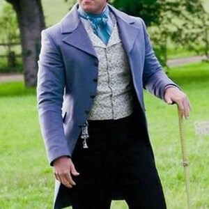 以下が含まれることがあります： 薄い青色のテールコート、模様入りのベスト、黒い半ズボン、黒いブーツを履いた男性が草むらに立っています。 彼は杖を持っています。 首には青いアスコットタイが見えます。 背景には木があり、屋外のシーンです。