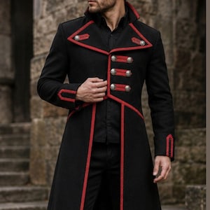 Peut inclure: Un long manteau noir avec un liseré rouge le long des revers, de l'ouverture avant et des poignets. Le manteau présente un design croisé avec des boutons argentés disposés en rangées sur le devant et des détails décoratifs aux épaules.