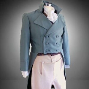 May include: A dusty blue double-breasted tailcoat jacket with wide lapels and six buttons, worn over a white cravat and a dark patterned vest. The ensemble includes light beige trousers, creating a formal outfit displayed on a mannequin.