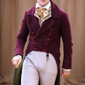 Könnte beinhalten: Ein weinroter Zweireiher mit fallendem Revers und passenden Knöpfen. Der Mantel wird mit einer gemusterten Weste und einem cremefarbenen Hemd kombiniert. Das Outfit beinhaltet eine helle Hose.