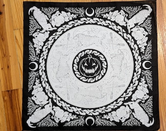 Puede incluir: Bandana negra con un diseño blanco que presenta una calabaza de Halloween, cabras y lunas crecientes. El diseño se repite alrededor de la bandana.