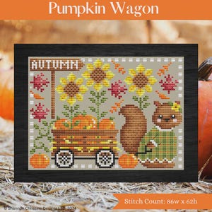 May include: Cross-stitch artwork titled "Pumpkin Wagon" in a black frame. The design features a wooden wagon filled with pumpkins, sunflowers, and a squirrel. The word "AUTUMN" is on a sign. The stitch count is 86w x 62h.