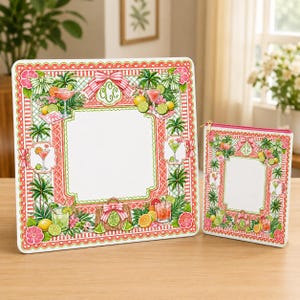 Op de afbeelding: Een decoratieve set met een groot vierkant frame en een kleinere rechthoekige etui met ritssluiting. Beide items hebben een wit midden met een rode en groene rand, versierd met cocktail illustraties, tropisch fruit en palmbomen.
