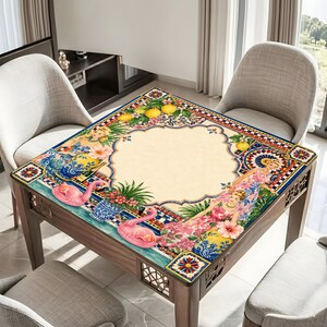 Pode incluir: Mesa quadrada de madeira com tampo decorativo com design de flamingo, floral e lim&atilde;o. A mesa tem um centro bege claro com uma borda estampada em azul, vermelho e amarelo. A mesa &eacute; rodeada por duas cadeiras.