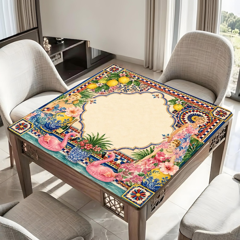 Pode incluir: Mesa quadrada de madeira com tampo decorativo com design de flamingo, floral e lim&atilde;o. A mesa tem um centro bege claro com uma borda estampada em azul, vermelho e amarelo. A mesa &eacute; rodeada por duas cadeiras.