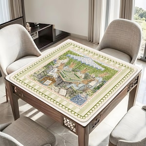 May include: A square table cover featuring a printed illustration of rabbits playing a board game outdoors under a blue and white umbrella. The border has a light green and white striped pattern with a scalloped edge and a decorative green vine motif.