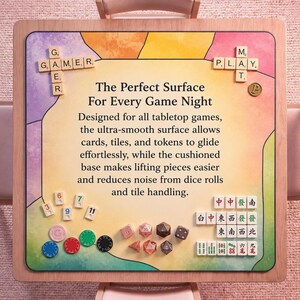 May include: A wooden-framed game board with a colorful surface, featuring the text "The Perfect Surface For Every Game Night." Includes game pieces like dice, tiles, and tokens. The board is designed for tabletop games.