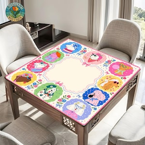 Può includere: Una tovaglia quadrata con un pannello centrale smerlato color crema circondato da un bordo di cornici circolari colorate. Ogni cornice contiene un'illustrazione di un cane in stile cartone animato in vari colori, tra cui rosa, blu, verde e giallo.