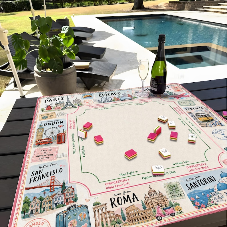 May include: A travel-themed board game with a beige playing surface featuring illustrations of famous landmarks like the Eiffel Tower and the London Eye. Pink and white game pieces are scattered across the board, with a bottle of champagne and a glass nearby.