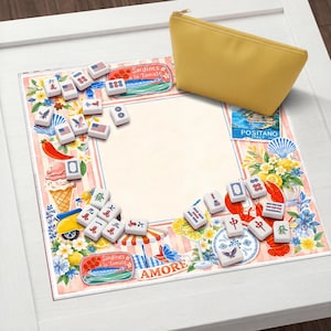May include: A yellow zippered pouch rests on a decorative Mahjong game mat. The mat features a border with Italian imagery, food illustrations, and Mahjong tiles. The game tiles are white with black symbols and red accents.