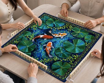 Könnte beinhalten: Eine quadratische Mahjong-Matte mit einer Teichszene, auf der drei Koi-Fische zwischen grünen Seerosenblättern auf einem tiefblauen Wasserhintergrund schwimmen. Die Matte ist von vier durchsichtigen Acryl-Haltern mit elfenbeinfarbenen Spielsteinen umgeben.