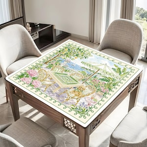 May include: A square wooden table with a decorative border and a painted tabletop scene. The scene depicts a sunny outdoor cafe with chairs, an umbrella, and a dog. The table is surrounded by chairs.