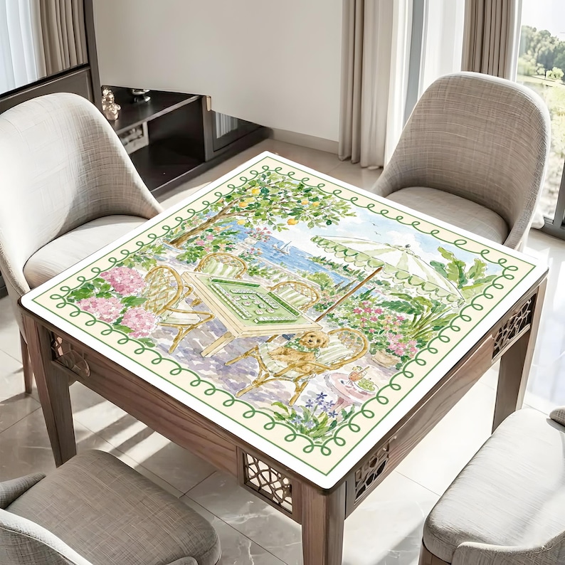 May include: A square wooden table with a decorative border and a painted tabletop scene. The scene depicts a sunny outdoor cafe with chairs, an umbrella, and a dog. The table is surrounded by chairs.
