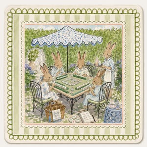 May include: A square decorative mat featuring a watercolor illustration of four rabbits playing mahjong at a table under a blue and white umbrella in a garden. A fifth rabbit serves drinks. A basket labeled Lucky Tile and a score pad are visible.