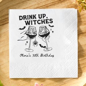 May include: White square paper napkin with the text "DRINK UP, WITCHES" in black. The design includes two wine glasses with spiderwebs, bats, and a spider. The text "Olivia's 30th Birthday" is below the graphic.