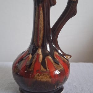 Op de afbeelding: Een witte keramische mok met een zwart handvat en de tekst "But First, Coffee" in een zwarte, handgeschreven lettertype. De mok staat op een wit oppervlak.