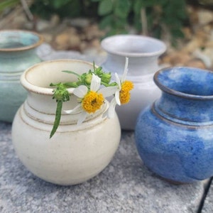 A grouping of miniature vases in 4 color options; green, yellow, white and blue