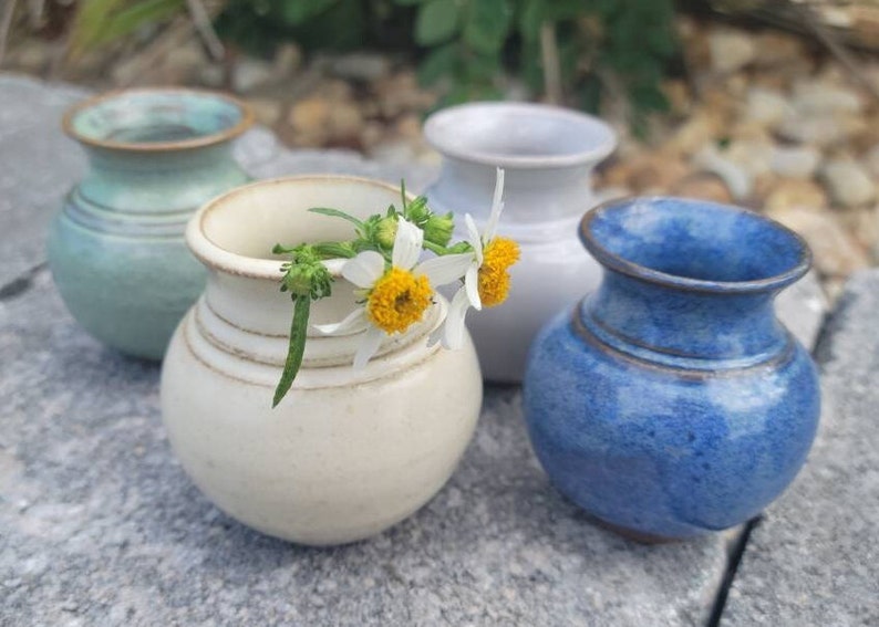 A grouping of miniature vases in 4 color options; green, yellow, white and blue