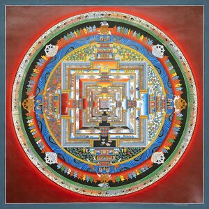 K&ouml;nnte beinhalten: Ein detailliertes, farbenfrohes Mandala-Gem&auml;lde mit einem quadratischen Zentrum und konzentrischen kreisf&ouml;rmigen Mustern. Das Kunstwerk weist rote, blaue, gr&uuml;ne und goldene Farbt&ouml;ne mit komplizierten geometrischen und symbolischen Designs auf. Das St&uuml;ck ist mit einem dunkelblauen Rand versehen.