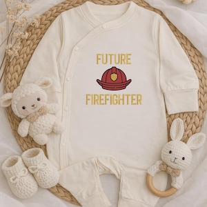 Può includere: Tutina per neonati color crema con la scritta "FUTURE FIREFIGHTER" e una grafica di un casco da pompiere rosso e oro. L'outfit è circondato da un peluche di agnello bianco, un paio di scarpine di lana bianche e un anello per la dentizione a forma di coniglio bianco.