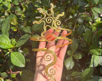 El brazalete Solara. Un brazalete dorado con forma de sol y piedra de cornalina.