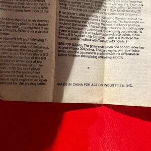 Puede incluir: Primer plano de una p&aacute;gina impresa con instrucciones del juego de domin&oacute;. El texto describe las reglas del juego, incluyendo c&oacute;mo puntuar y finalizar la partida. El texto incluye la frase "MADE IN CHINA FOR ACTION INDUSTRIES, INC.".
