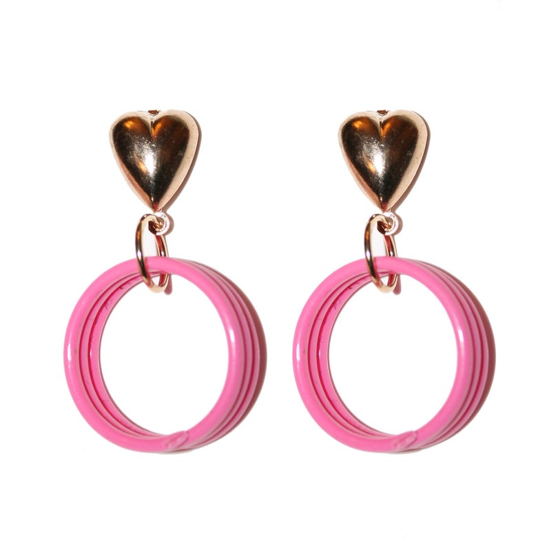May include: A pair of pink hoop earrings with a gold heart charm at the top.