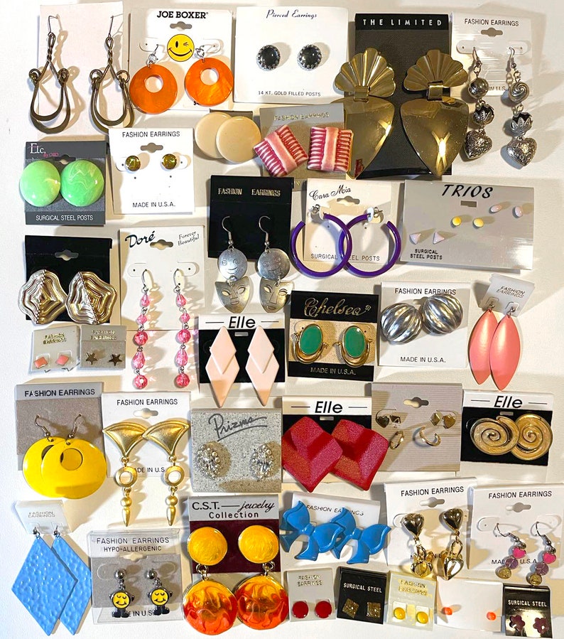Puede incluir: Una colecci&oacute;n de varios pendientes de moda, que incluyen aros, tachuelas y colgantes. Los pendientes vienen en una variedad de colores, formas y materiales, como oro, plata y pl&aacute;stico. Algunos pendientes tienen texto en el embalaje.