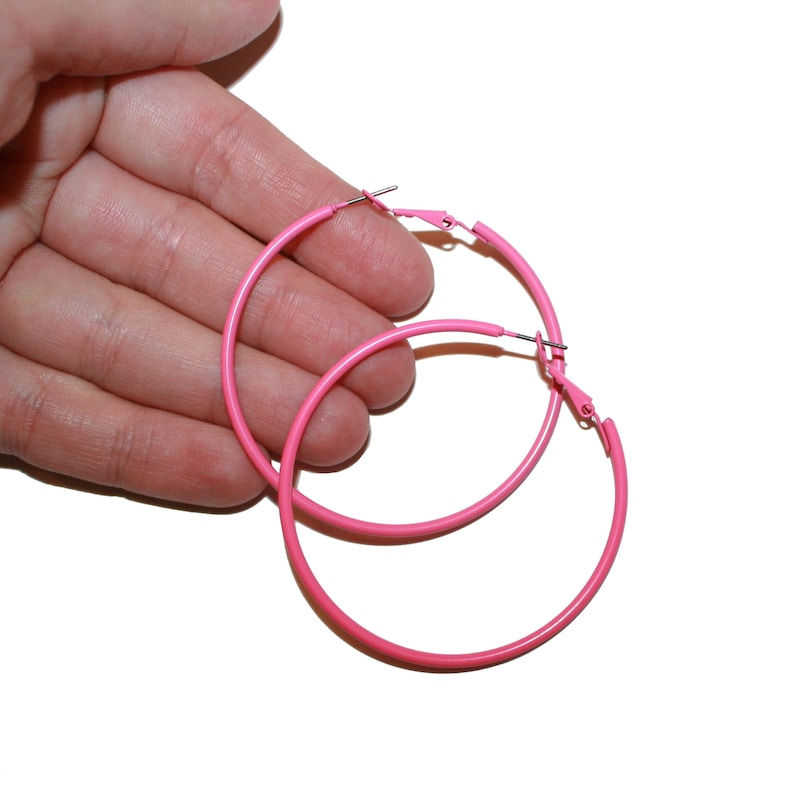 May include: A pair of pink hoop earrings. The earrings are made of metal and have a simple, circular design.