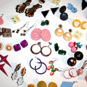Puede incluir: Una colecci&oacute;n de pendientes vintage de varios estilos y colores. Incluye pendientes dorados, plateados, rosas, morados, verdes y negros. Los estilos incluyen aros, tachuelas, colgantes y clip. Algunos pendientes son geom&eacute;tricos, otros presentan dise&ntilde;os florales o abstractos. Se ven varios materiales.