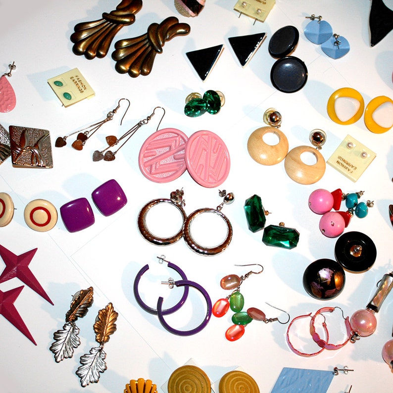 Puede incluir: Una colecci&oacute;n de pendientes vintage de varios estilos y colores. Incluye pendientes dorados, plateados, rosas, morados, verdes y negros. Los estilos incluyen aros, tachuelas, colgantes y clip. Algunos pendientes son geom&eacute;tricos, otros presentan dise&ntilde;os florales o abstractos. Se ven varios materiales.