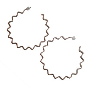 May include: A pair of silver hoop earrings with a wavy, zig-zag design.