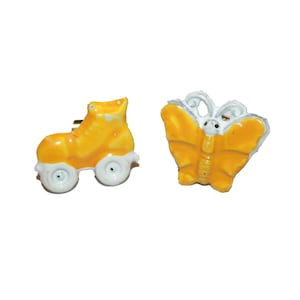 May include: Two small, decorative pins. One is a yellow roller skate with white wheels. The other is a yellow butterfly with white accents. Both pins have a glossy finish and are set against a white background.
