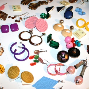 Puede incluir: Una colecci&oacute;n de pendientes vintage en varios estilos y colores, incluyendo aros, tachuelas y pendientes colgantes. Los pendientes est&aacute;n hechos de diferentes materiales, como metal, pl&aacute;stico y cuentas. Los colores incluyen p&uacute;rpura, rosa, verde y amarillo.