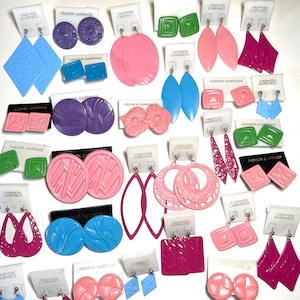 May include: Assortment of colorful plastic earrings on white cards with the text "Fashion Earrings". The earrings are in various shapes, including circles, squares, ovals, and flowers.