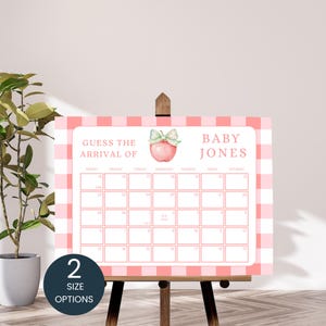 May include: A pink and white gingham baby shower calendar on a wooden easel. The calendar has a pink apple graphic and the text "GUESS THE ARRIVAL OF BABY JONES." A dark blue circle with the text "2 SIZE OPTIONS" is in the lower left corner.