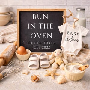 Peut inclure: Une ardoise avec le texte "BUN IN THE OVEN" et "FULLY COOKED JULY 202X" est entourée d'articles pour bébés. Un body blanc avec "BABY Williams" est présenté avec des chaussures de bébé, une sucette, un lapin en peluche et des ustensiles de cuisine.