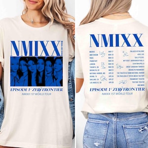 May include: Cream-colored t-shirt featuring the band name "NMIXX" in blue, along with the text "EPISODE 1: ZERO FRONTIER" and "NMIXX 1ST WORLD TOUR." The front displays a blue-toned image of the band members. The back lists tour dates and locations.