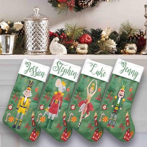 Puede incluir: Cuatro calcetines navideños personalizados con los nombres Jessica, Stephen, Luke y Jenny. Cada calcetín verde presenta un personaje diferente con temática de Cascanueces, incluyendo un soldado, un ratón, una bailarina y otro soldado. Bastones de caramelo y casas decoran los calcetines.