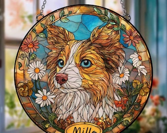 May include: Round stained glass window featuring a dog with brown and white fur, blue eyes, and a pink nose. The dog is surrounded by daisies and other flowers. The name "Millo" is displayed on the bottom.