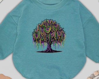 May include: A teal baby romper featuring a tree design with colorful beads. The tree has a purple trunk and branches, with strands of green, gold, and purple beads hanging down. The word "BABY" is spelled out in wooden letters.