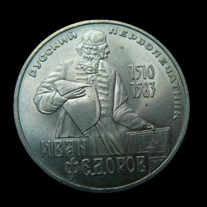 May include: A silver coin featuring a portrait of a man with a beard, holding a book. The coin has text in a foreign language, with the years 1510 and 1583. The coin is set against a black background.