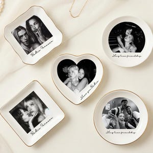 Op de afbeelding: Een verzameling witte keramische schaaltjes in verschillende vormen, waaronder vierkant, rond en hartvormig. Elk schaaltje heeft een zwart-witfoto en een gouden rand. Tekst op de schaaltjes luidt "Bestie Forever" en "Longtime friendship."