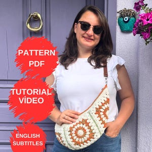 以下が含まれることがあります： クリームとオレンジ色のかぎ針編みバッグ、茶色の革ストラップ付き。 バッグは幾何学模様です。 画像には、赤い背景に「PATTERN PDF」、「TUTORIAL VIDEO」、「ENGLISH SUBTITLES」というテキストも含まれています。