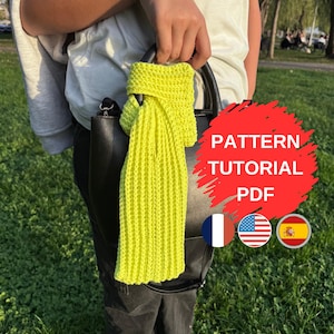 May include: A vibrant neon yellow knitted scarf hangs over a black handbag. The scarf features a ribbed knit design. The image includes the text "PATTERN TUTORIAL PDF" with flags of France, the United States, and Spain.