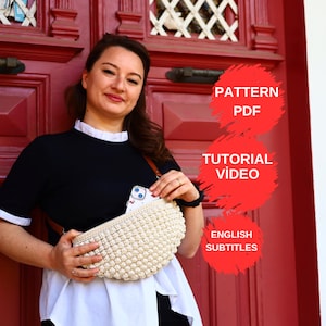 以下が含まれることがあります： クリーム色の、かぎ針編みのバッグを、茶色のストラップで持っている女性。バッグは丸みを帯びた形で、質感のある、バブルのようなデザインです。画像には「PATTERN PDF」、「TUTORIAL VIDEO」、「ENGLISH SUBTITLES」というテキストも含まれています。