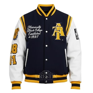 May include: A navy blue and white varsity jacket with yellow accents. The jacket features the text "Historically Black College Established de 1897" and a large "AT" logo. The sleeves have the numbers "18" and "11".